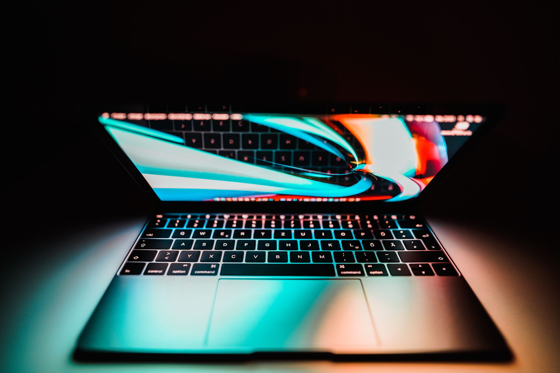 Close-up of a laptop with a colorful screen in low light